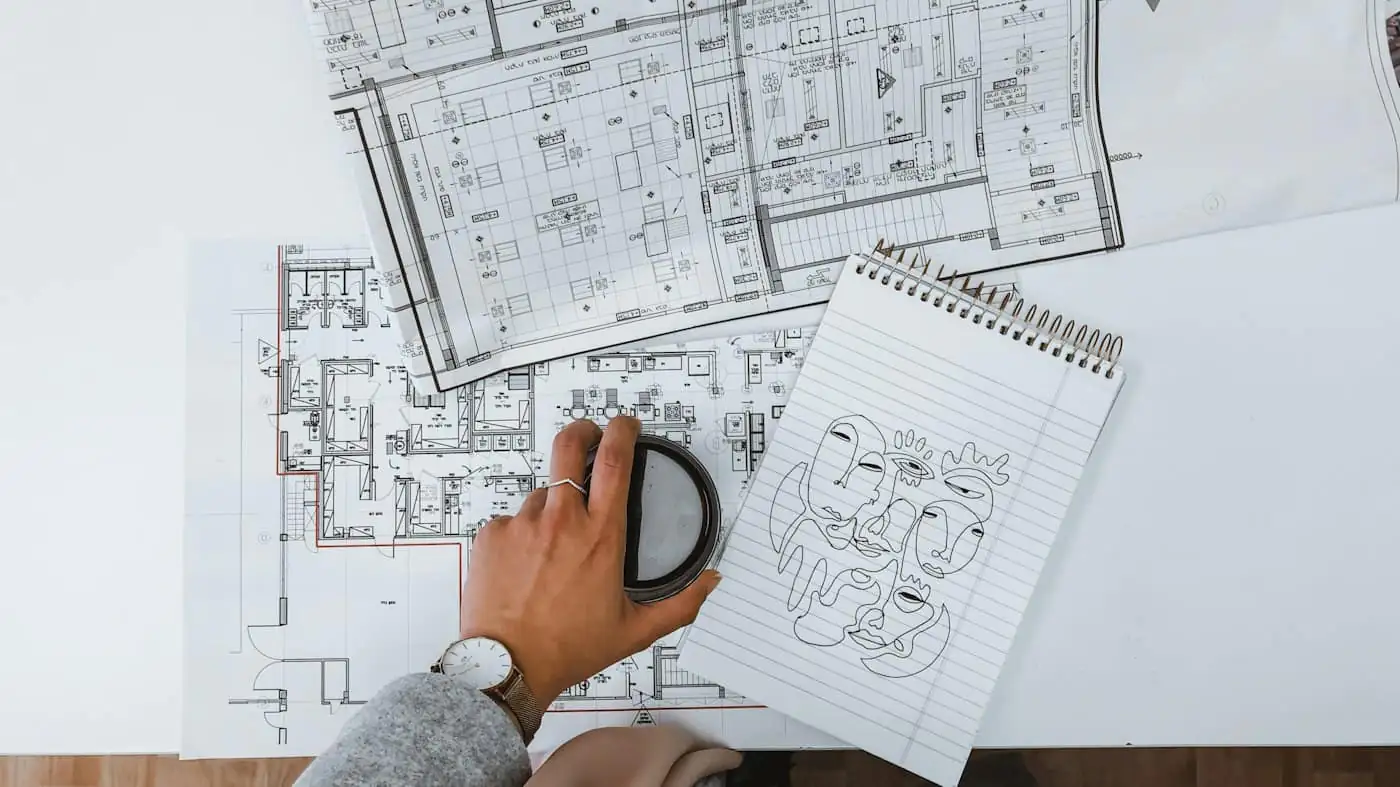 Draughtsman reviewing printed architectural drawings of a house on a desk
