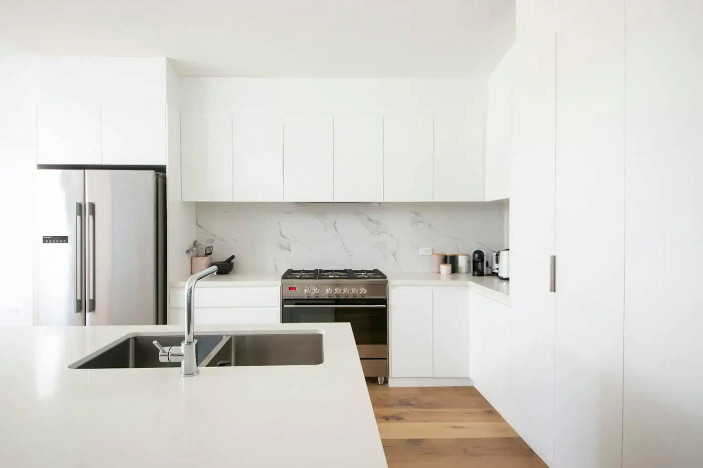 New kitchen in the extension with white cabinets, tiled walls and a stainless steel hob