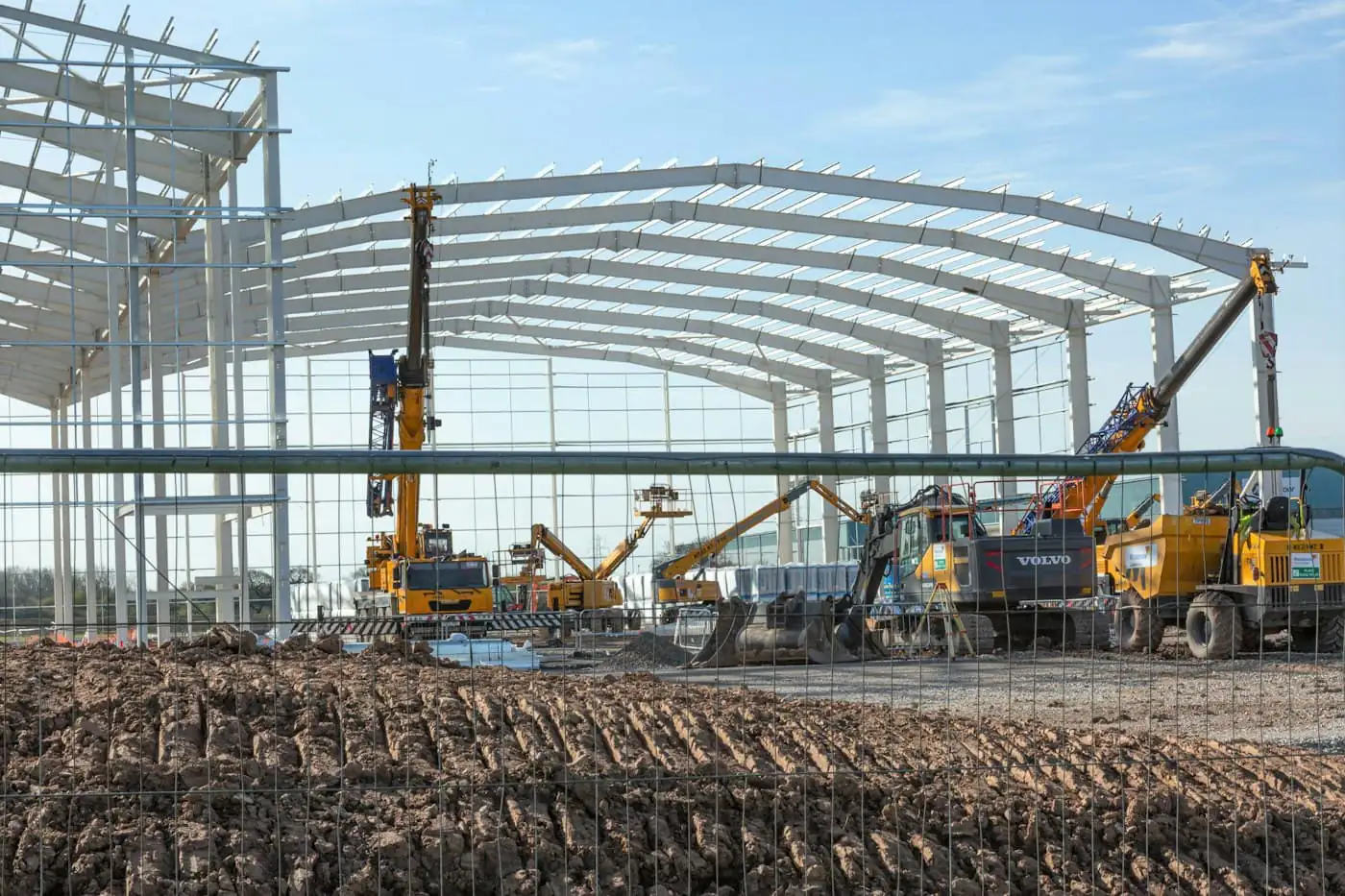 Steel portal frame of a warehouse with workers fixing roof purlins